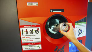 Berlin, Germany - August 31, 2015: Unrecognizable woman throwing empty beer can in recycling machine in order to receive deposit given while paying at the till. In Germany prices are formed on the principle that customar adds 0.08â‚¬ when buying drink in glass bottle, while 0.25â‚¬ should be added on the beverage price if it is packed in can or plastic bottle. By recycling later on, you receive coupon with that amount which is cashable at the till in any store.