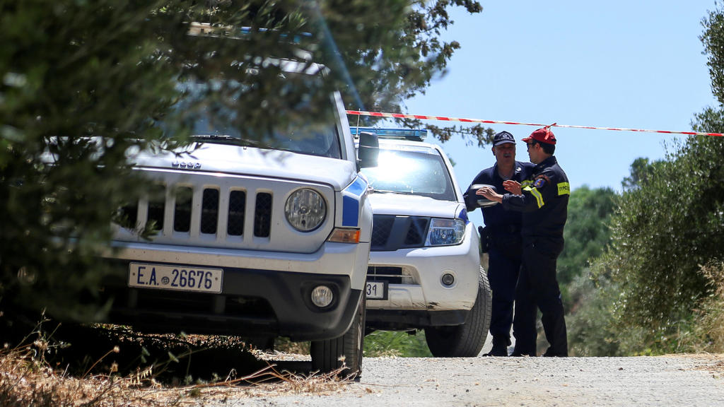A police officer and a member of a fire brigade search and rescue team stand behind a police cordon, in an area where the body of a woman was found, near the village of Kolimpari on the island of Crete, Greece, July 9, 2019. REUTERS/Makis Kartsonakis