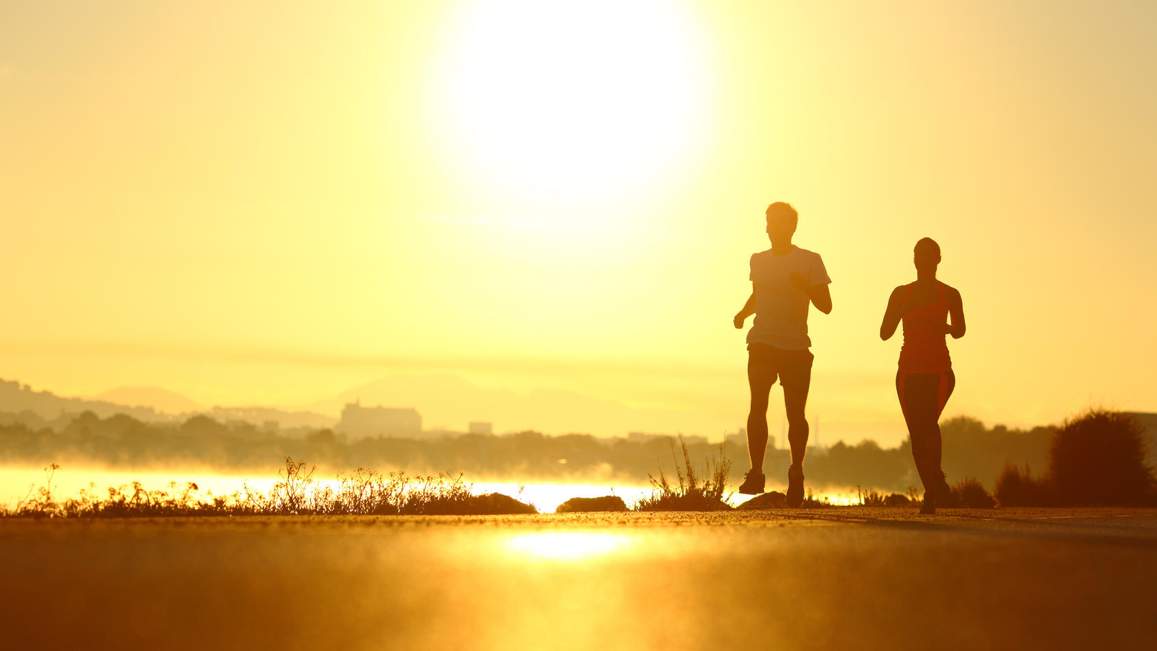 Mann und Frau laufen im Sonnenaufgang