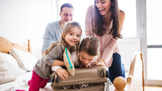 Portrait of a young happy family with two children packing for holiday at home.