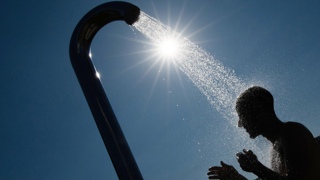 24.07.2019, Nordrhein-Westfalen, Bielefeld: Ein Mann duscht sich im Gegenlicht der Sonne unter einer Brause in einem Freibad. Foto: Friso Gentsch/dpa +++ dpa-Bildfunk +++