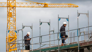 08.07.2019, Niedersachsen, Hannover: Zwei Bauarbeiter gehen auf einer Baustelle auf einem Hausdach auf dem Gerüst. Bauminister Lies (SPD) hat am Montag (08.07.2019) die Ergebnisse des Wohnungsmarktberichts 2018/19 für Niedersachsen vorgestellt. Foto: Cindy Riechau/dpa +++ dpa-Bildfunk +++