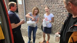 Sevelen (Issum): Zwei Frauen bieten zwei Feuerwehrmännern Kaffee an.