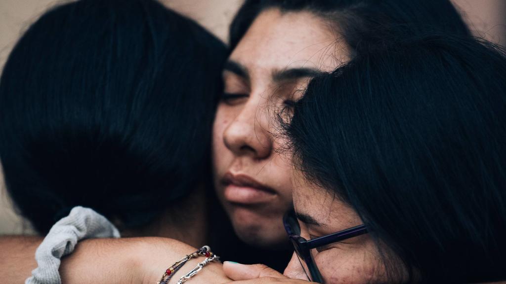 Three women embrace after a vigil at St. Pius X Church following a mass shooting at Walmart and the Cielo Vista Mall in El Paso, Texas on Saturday, August 3, 2019. Twenty people were killed and dozens injured as a gunman opened fire in the crowded st