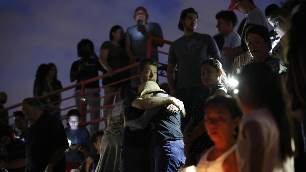 03.08.2019, USA, El Paso: Menschen umarmen sich während einer Mahnwache nachdem ein Schütze in einem Einkaufszentrum mindestens 20 Menschen getötet und mindestens 26 weitere verletzt hatte. Es gibt Hinweise, dass es sich um ein Hassverbrechen handeln
