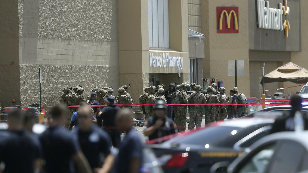 03.08.2019, USA, El Paso: Mitglieder einer Spezialeinheit und Polizisten stehen vor dem Eingang eines Ladenkomplexes, in dem ein Mann zahlreiche Menschen erschossen hat. Die Hintergründe der Tat blieben zunächst unklar. Foto: Mark Lambie/The El Paso
