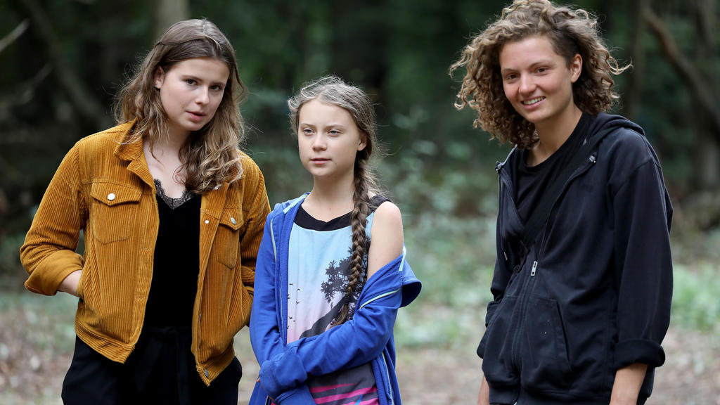 10.08.2019, Nordrhein-Westfalen, Kerpen: Greta Thunberg (M), Klimaschutzaktivistin, steht mit Luisa Neubauer (l), der deutschen Organisatorin der Klimastreiks «Fridays for Future» und der Aktivistin «Indigo» (r) im Haibaches Forst. Die Schwedin hat d