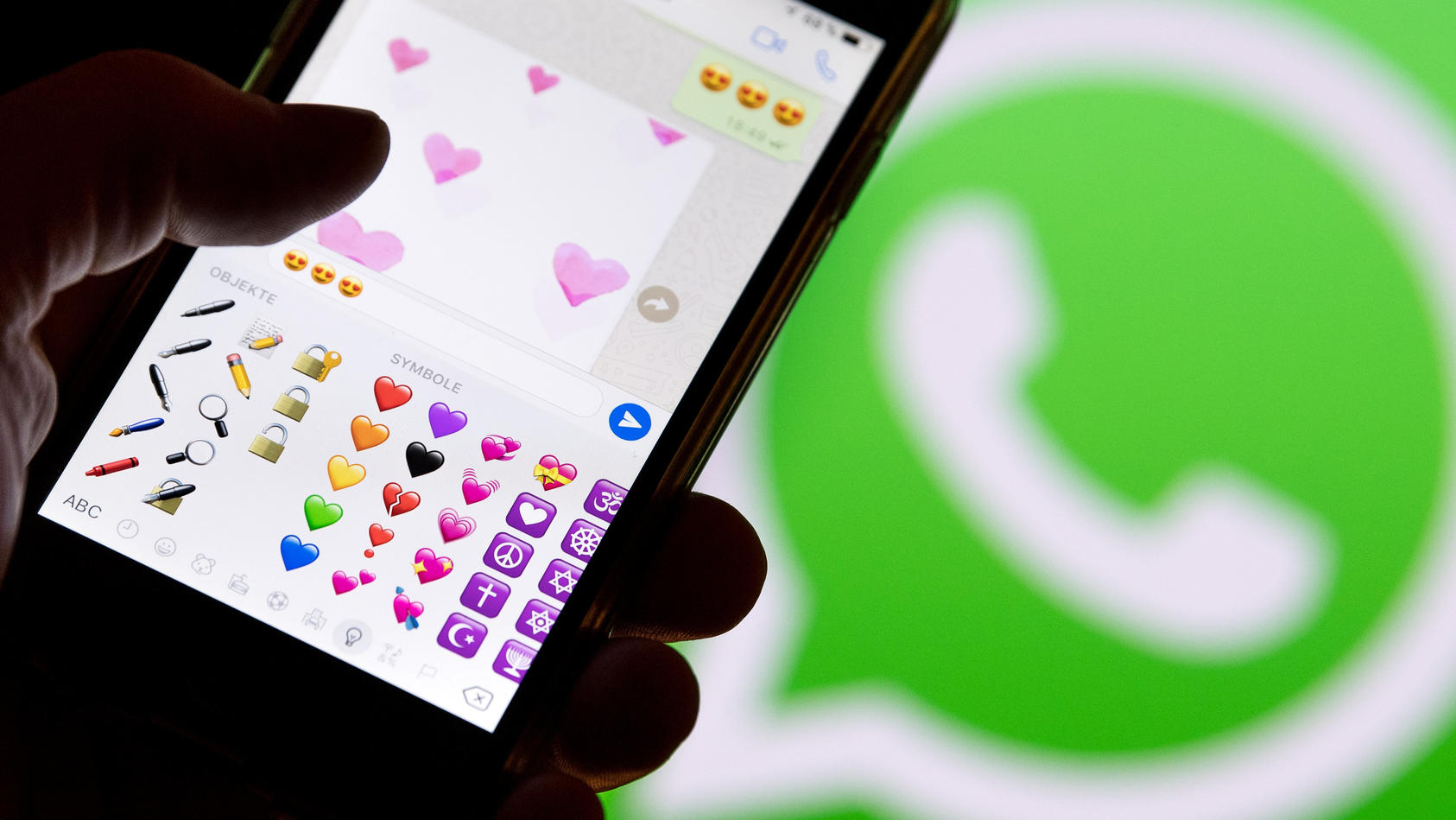 ILLUSTRATION - 12.02.2018, Hessen, Frankfurt am Main: Ein Smartphone mit Emojis aus WhatsApp vor dem WhatsApp-Logo. (Zu dpa: «Liebe in Zeiten von WhatsApp - «Schatz» ist noch immer Nummer eins» vom 13.02.2018) Foto: Fabian Sommer/dpa +++ dpa-Bildfunk