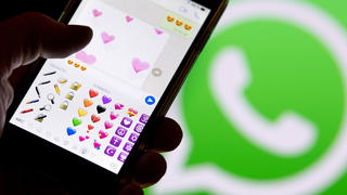 ILLUSTRATION - 12.02.2018, Hessen, Frankfurt am Main: Ein Smartphone mit Emojis aus WhatsApp vor dem WhatsApp-Logo. (Zu dpa: «Liebe in Zeiten von WhatsApp - «Schatz» ist noch immer Nummer eins» vom 13.02.2018) Foto: Fabian Sommer/dpa +++ dpa-Bildfunk +++