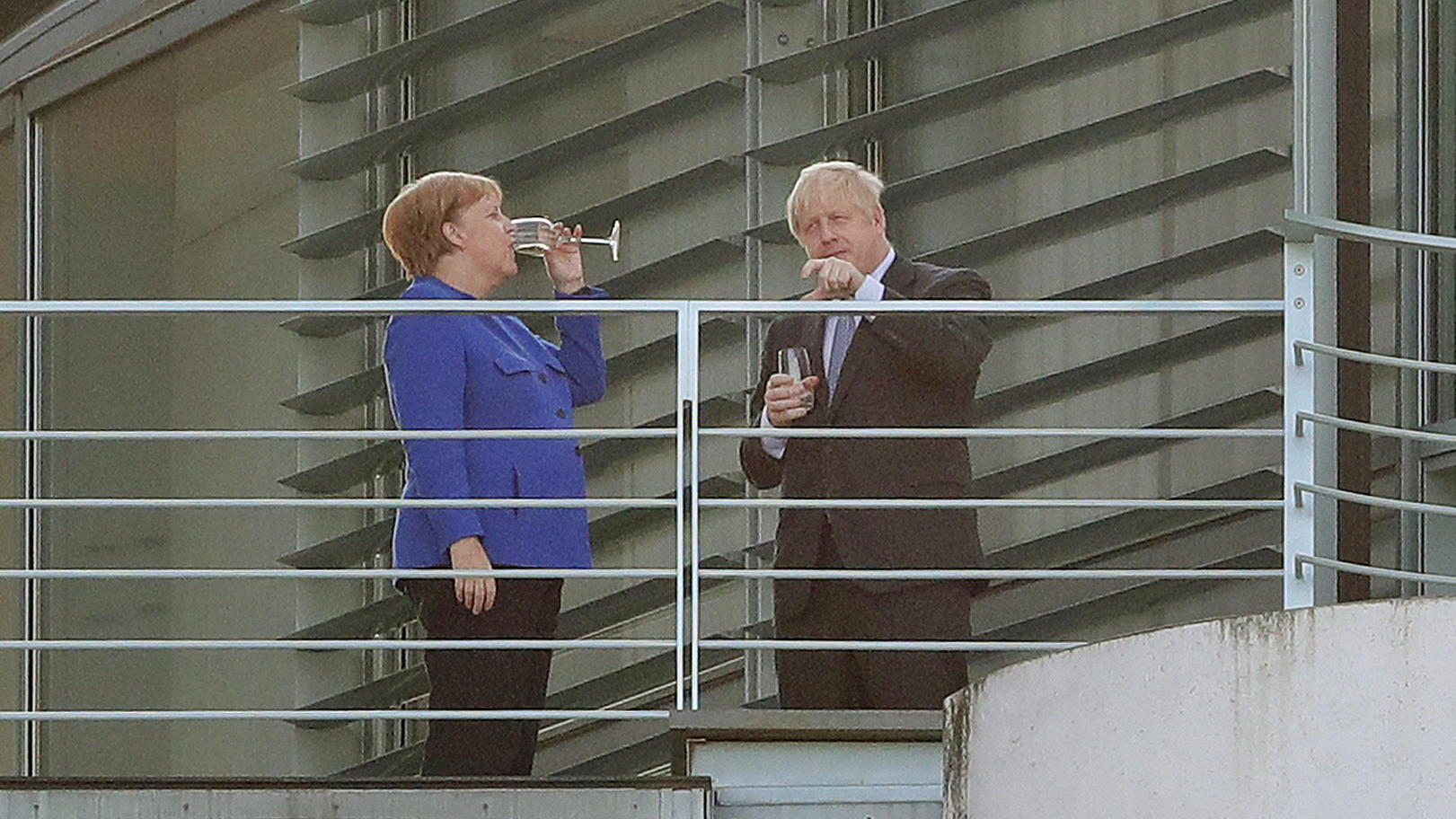 Bundeskanzlerin Angela Merkel (CDU) trinkt mit Boris Johnson, Premierminister von Großbritannien, bei ihrem Treffen im Bundeskanzleramt auf einem Balkon ein Getränk.