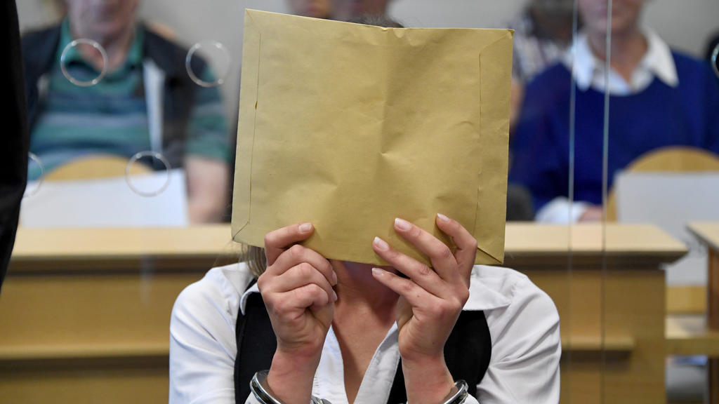22.08.2019, Schleswig-Holstein, Itzehoe: Mit verdecktem Gesicht sitzt die Angeklagte zum Auftakt eines Mordprozesses im Gerichtssaal. Die 37-Jährige Angeklagte und der 47-Jährige Angeklagte sollen im April 2017 den damaligen Partner der Frau umgebrac