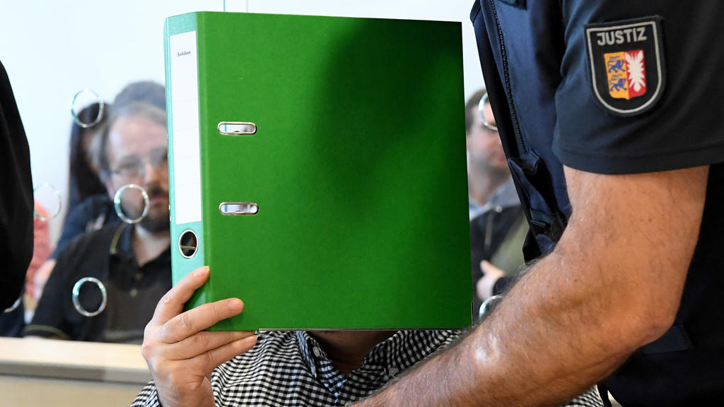 22.08.2019, Schleswig-Holstein, Itzehoe: Mit verdecktem Gesicht sitzt der Angeklagte zum Auftakt eines Mordprozesses im Gerichtssaal. Die 37-Jährige Angeklagte und der 47-Jährige Angeklagte sollen im April 2017 den damaligen Partner der Frau umgebrac