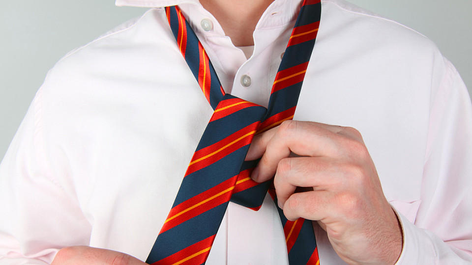Mann bindet eine blau-rot gestreifte Krawatte