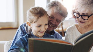 Großeltern und Enkel lesen ein Buch
