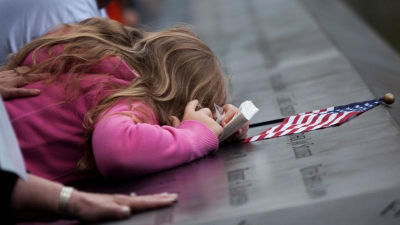 A girl leans over the panels with the victims' names inscribed at the south pool of the 9/11 Memorial during the tenth anniversary ceremonies at the site of the World Trade Center September 11, 2011, in New York, USA. EPA/TODD HEISLER / P