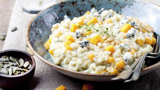 Pumpkin, blue cheese risotto in a blue ceramic plate on a wooden background