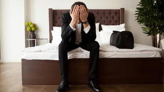 Mann im Anzug sitzt traurig in Hotelzimmer