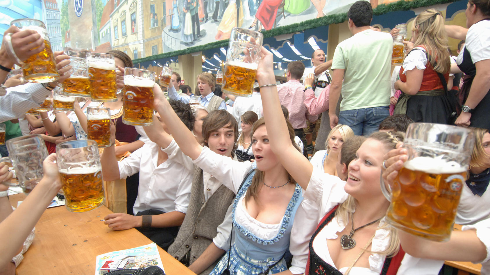 Junge Besucher stoßen bei Oktoberfest mit Maß Bier an