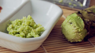 Selective focus imaga of grated fresh wasabi root also called Japanese horseradish on a bamboo mat with soy sauce.