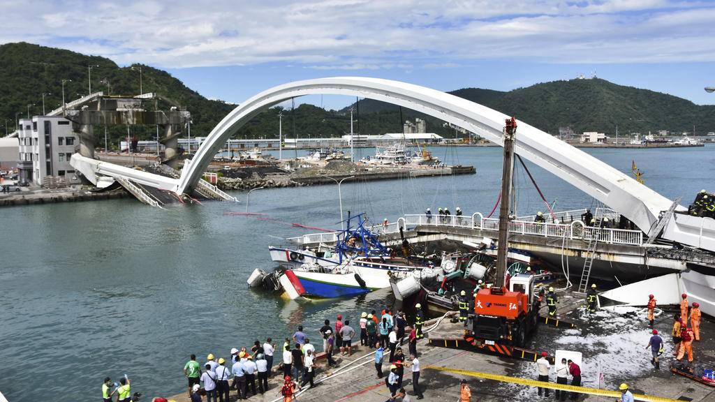 01.10.2019, Taiwan, Nanfangao: Feuerwehrleute und Rettungskräfte arbeiten am Unfallort nach dem Einsturz einer Brücke. Taifun «Mitag» hat in Taiwan eine Brücke einstürzen lassen und auch weitere schwere Schäden hervorgerufen. Nach Angaben der Nationa