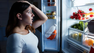 Junge Frau entsetzt vor Kühlschrank
