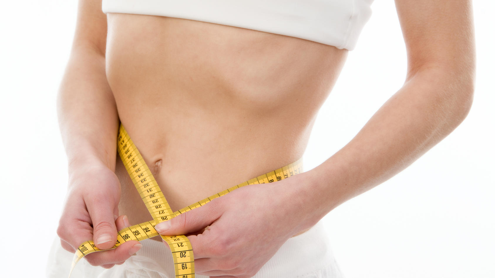 Untergewichtige junge Frau misst Taillenumfang