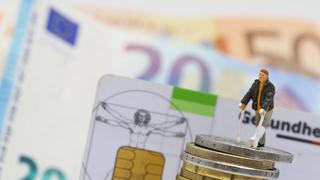  Nuernberg Symbolfoto, Themenbild Krankenversicherung, Krankenkassenbeitrag, Mann mit Gips und Gehhilfe steht auf Euro Muenzen. Im Hintergrund eine Gesundheitskarte der Barmer gek sowie Euro Banknoten. Copyright: xWuestx/Eibner-Pressefotox EPfwt
