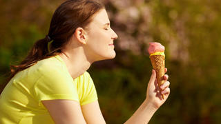Lachende Frau isst Eiscreme in der Waffel im Sommer