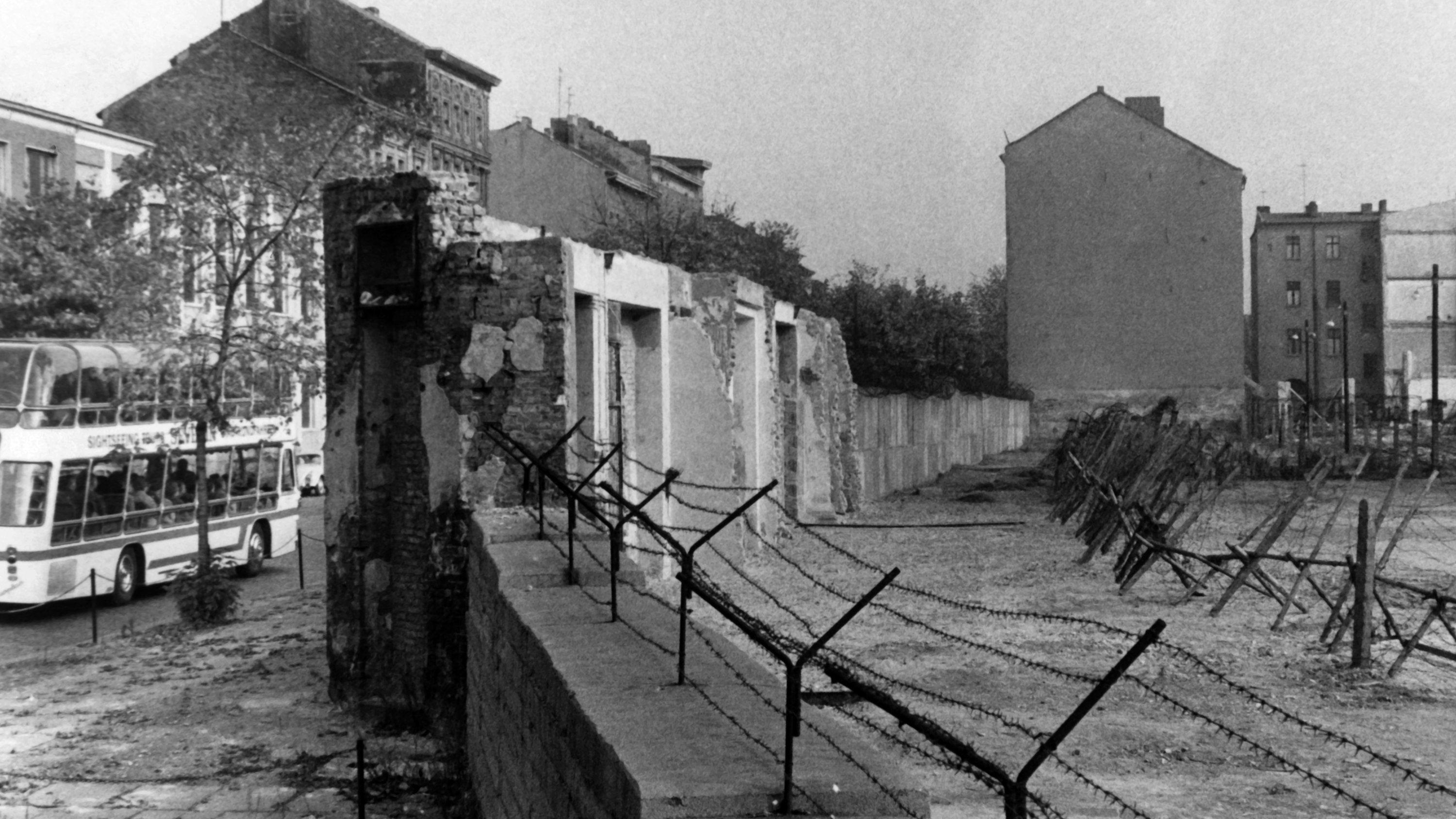 ARCHIV - Blick auf die Berliner Mauer mit Sperranlagen und Todesstreifen am 22.10.1965 in der Bernauer Straße in Berlin-Wedding. Gut zu erkennen sind auch noch die Reste der Häuser die nach und nach für den Mauerbau abgerissen wurden. Jahrestage des 