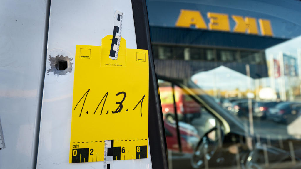 dpatopbilder - 09.11.2019, Hessen, Frankfurt/Main: Ein geparktes Fahrzeug mit einem von der Spurensicherung gekennzeichnetem Einschussloch steht vor einem Seiteneingang eines Ikea-Möbelhauses im Stadtteil Nieder-Eschbach, nachdem ein Geldbote angesch