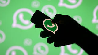FILE PHOTO: A man poses with a smartphone in front of displayed Whatsapp logo in this illustration picture September 14, 2017. REUTERS/Dado Ruvic/File Photo