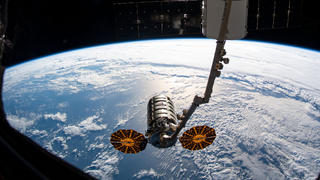 HANDOUT - 06.08.2019, ---, Weltall: ARCHIV - Der Roboterarm Canadarm2 ist ausgefahren, um den Cygnus-Raumtransporter (unten, Mitte) an der Internationalen Raumstation ISS festzuhalten. Mit mehr als 3700 Kilogramm Nachschub und technischer Ausstattung an Bord ist der private Raumfrachter «Cygnus» erneut zur Internationalen Raumstation ISS gestartet. Foto: Nasa/dpa - ACHTUNG: Nur zur redaktionellen Verwendung und nur mit vollständiger Nennung des vorstehenden Credits +++ dpa-Bildfunk +++