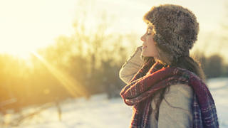 Junge Frau schaut in die Wintersonne