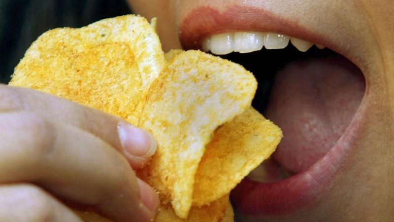 Eine junge Frau isst Kartoffelchips (Symbolbild aufgenommen am 4.12.2002 in Düsseldorf). Der Anteil des Krebs erregenden Stoffes Acrylamid ist in einigen Lebensmitteln nach Angaben des Verbraucherschutzministeriums bereits gesunken. So sei es etwa be