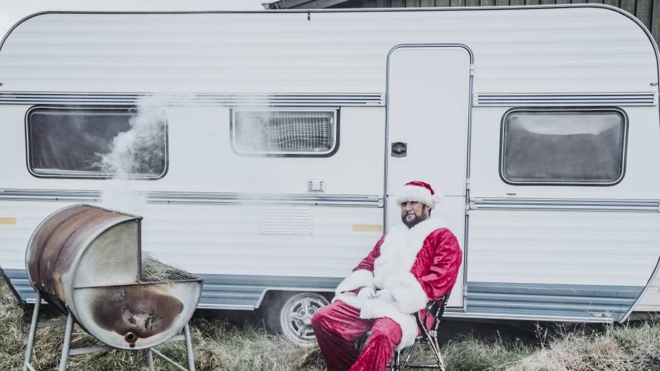 Weihnachtsmann vor einem Wohnwagen