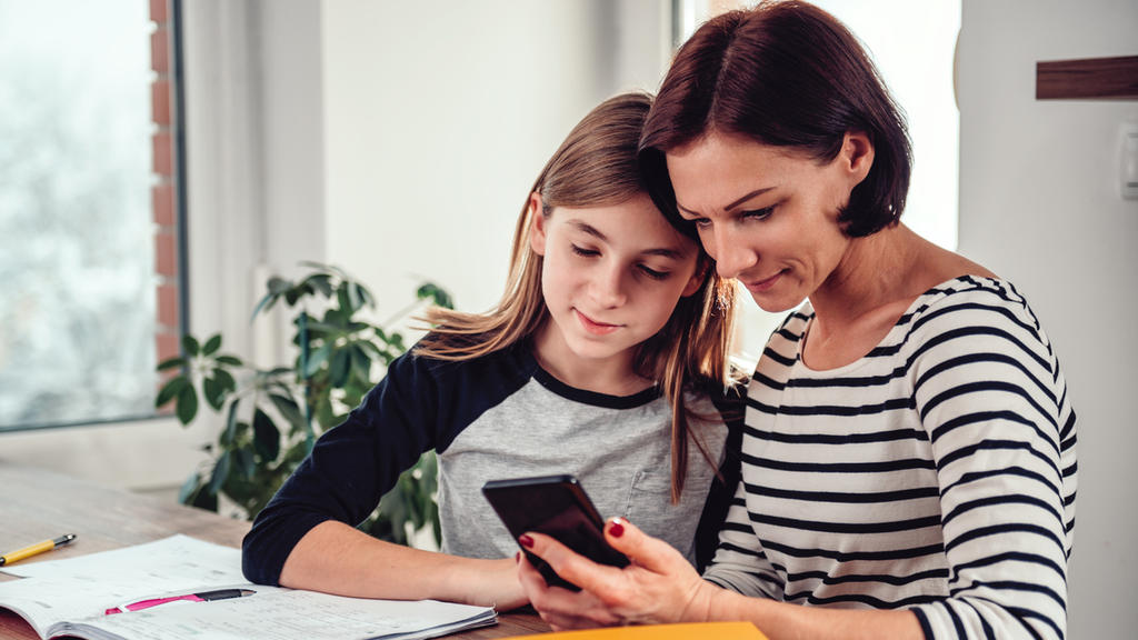 Mutter und Tochter schauen zusammen auf Smartphone