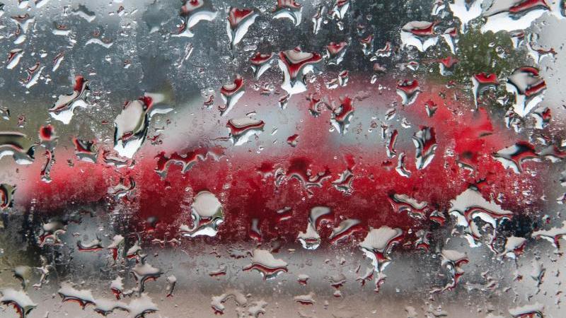 Ein Auto ist hinter einer nassen Autoscheibe zu sehen