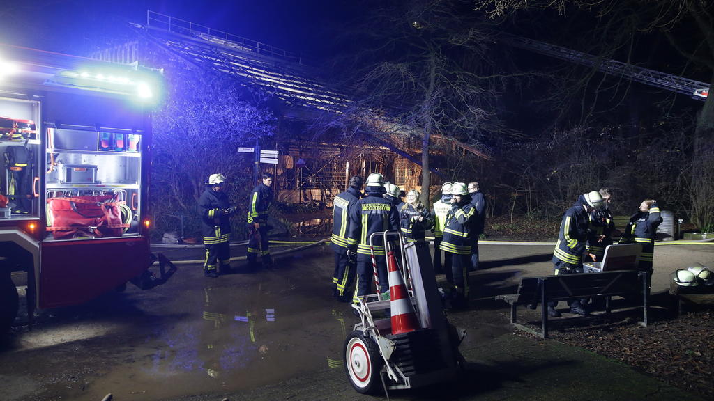 01.01.2020, Nordrhein-Westfalen, Krefeld: Feuerwehrleute stehen nach Löscharbeiten vor dem Affenhaus im Krefelder Zoo. Foto: David Young/dpa +++ dpa-Bildfunk +++