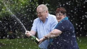 Colin Weir (R) and his wife Chris spray a bottle of champagne after a news conference at a hotel near Falkirk, Scotland July 15, 2011. The couple scooped 161 million pounds ($259 million) in Tuesday's Euromillions jackpot.   REUTERS/David Moir (BRITA