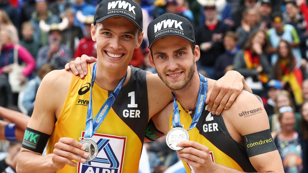 ARCHIV - 07.07.2019, Hamburg: Beach-Volleyball, Weltmeisterschaft, im Rothenbaum Stadion: Finale, Männer, Krasilnikov/Stojanowskiy (Russland) - Thole/Wickler (Deutschland). Julius Thole (l) und Clemens Wickler präsentieren bei der Siegerehrung ihre S