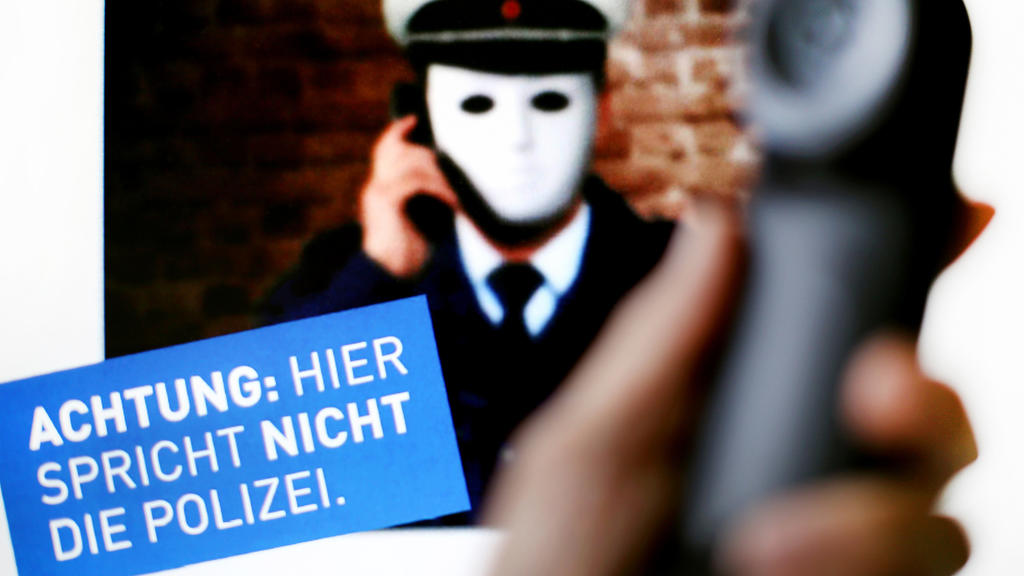 ARCHIV - 11.10.2017, Nordrhein-Westfalen, Düsseldorf: Ein Telefonhörer ist vor einem Plakat der Polizei NRW mit der Aufschrift «Achtung: Hier spricht NICHT die Polizei» zu sehen. Mit der Betrugsmasche «falscher Polizist und Amtsträger» haben die Erm