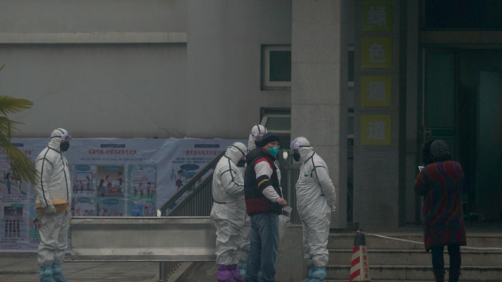 21.01.2020, China, Wuhan: Mitarbeiter in Schutzanzügen stehen vor dem Wuhan Medical Treatment Center, in dem ein Patient mit Verdacht auf den neuartigen Corona-Virus behandelt wurde. Foto: Dake Kang/AP/dpa +++ dpa-Bildfunk +++