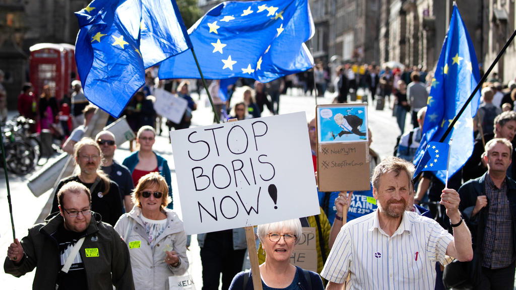 Großbritannien, Edinburgh: Pro-Europäische Demonstranten protestieren mit der Flagge der Europäischen Union sowie einem Plakat mit der Aufschrift «Stop Boris Now!» (Stoppt Boris jetzt!)