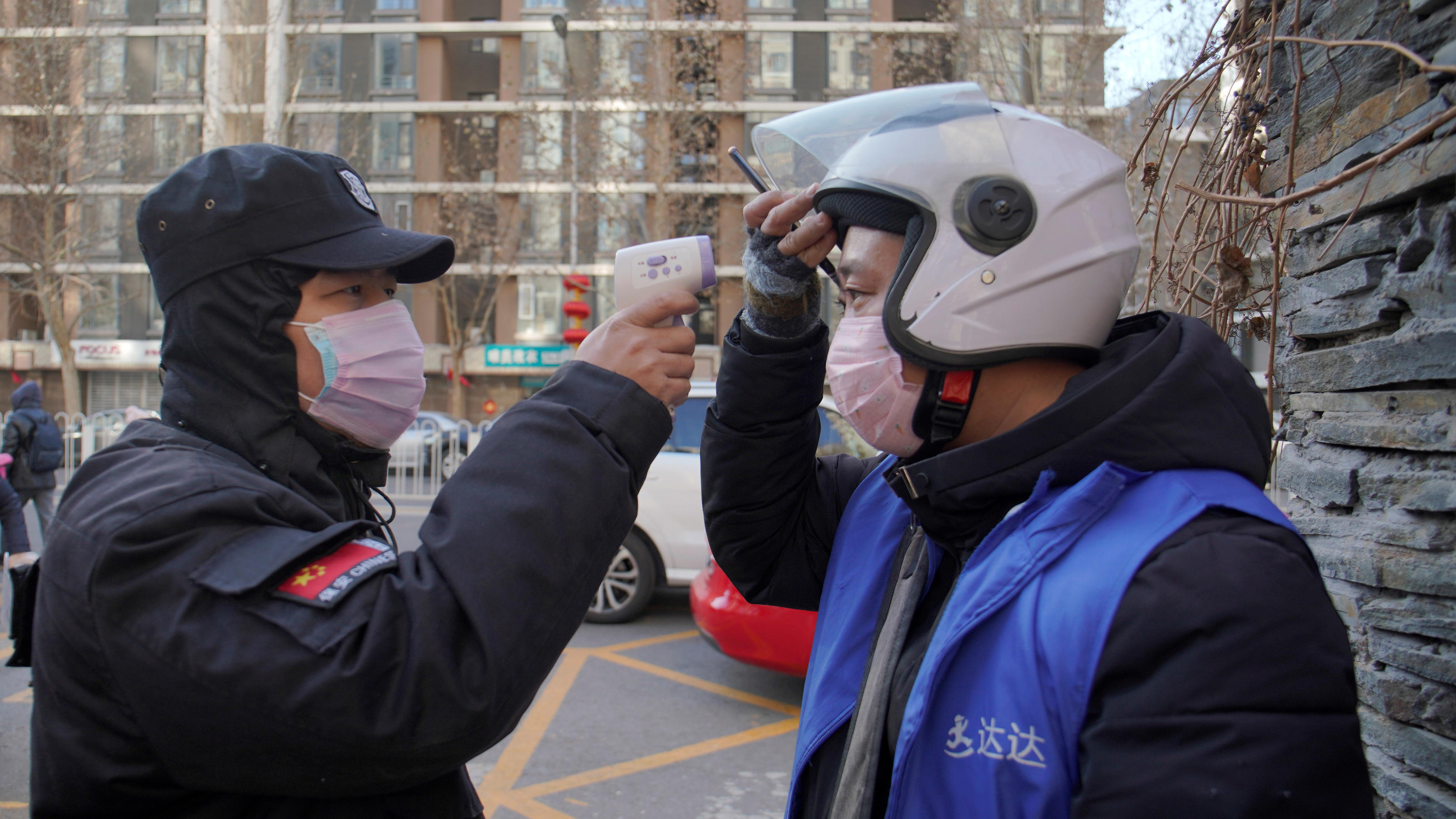 A security officer takes body temperature measurement of a delivery worker at a residential compound in Beijing, China as the country is hit by an outbreak of the new coronavirus, February 1, 2020.  REUTERS/Stringer  NO RESALES. NO ARCHIVES.