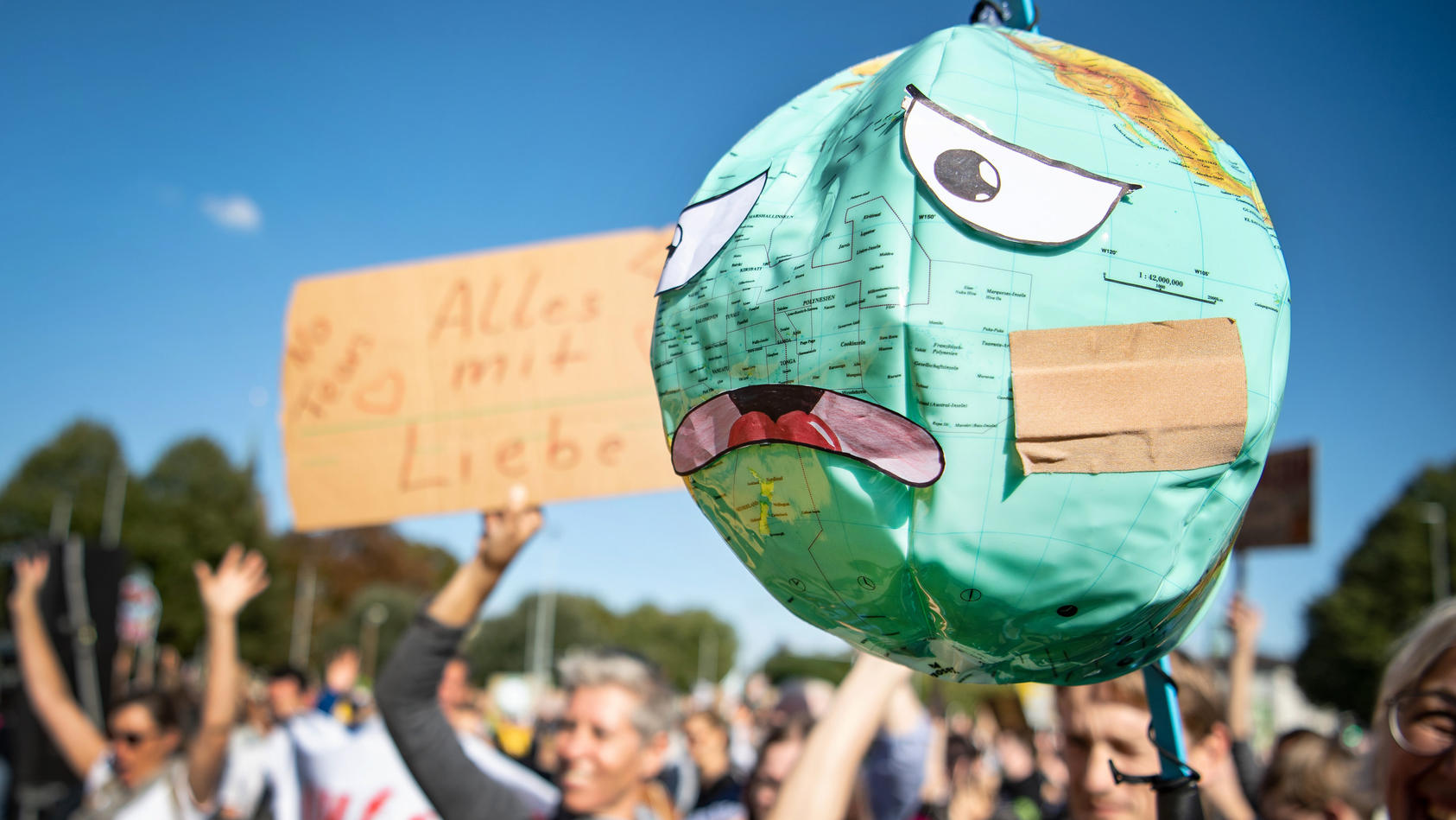 Klima-Demonstranten halten einen Luftballon mit Globusaufdruck. 