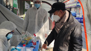 Volunteers in protective suits help a man with registration at a checkpoint of a residential compound, following the outbreak of the novel coronavirus in Wuhan, Hubei province, China February 9, 2020. Picture taken February 9, 2020. China Daily via REUTERS  ATTENTION EDITORS - THIS IMAGE WAS PROVIDED BY A THIRD PARTY. CHINA OUT.