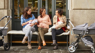 Drei junge Mütter mit Kinderwagen unterhalten sich