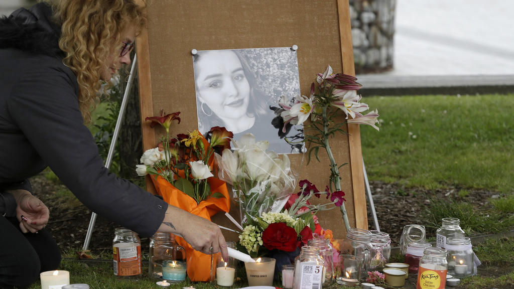 FILE - In this Dec. 12, 2018, file photo, a woman lights candles during a candlelight vigil for murdered British tourist Grace Millane at Cathedral Square in Christchurch, New Zealand. At a sentencing hearing at the Auckland High Court on Friday Feb.