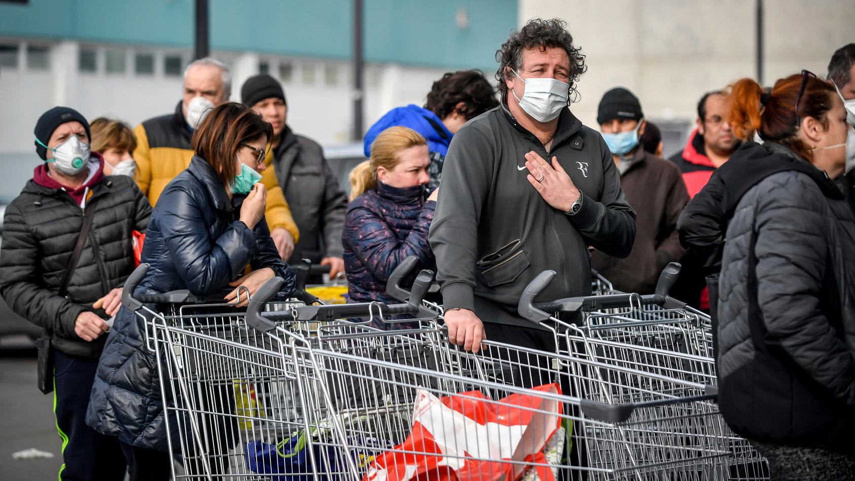 dpatopbilder - 23.02.2020, Italien, Casalpusterlengo: Menschen tragen Atemschutzmasken und stehen vor einem Supermarkt in einer Schlange. Nach dem Tod zweier Menschen sind Teile des öffentlichen Lebens zum Erliegen gekommen. Kein europäisches Land ha