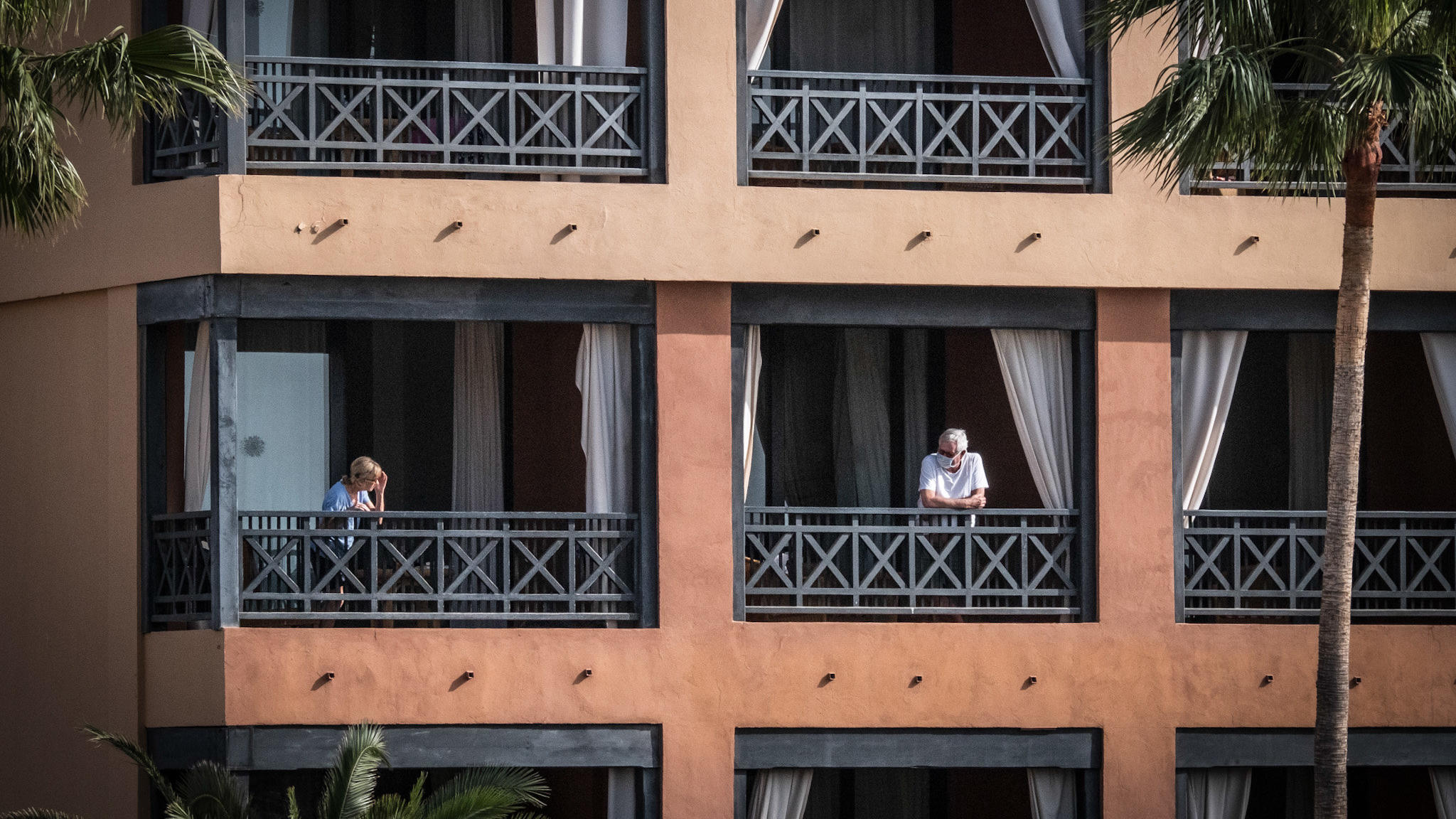 27.02.2020, Spanien, Santa Cruz de Tenerife: Das Hotel H10 Costa Adeje Palace, auf dessen Balkon Gäste stehen. Das wegen Coronavirus-Fällen unter Quarantäne gestellte Hotel auf Teneriffa ist weiterhin durch die Polizei abgeriegelt. Foto: Arturo Rodri